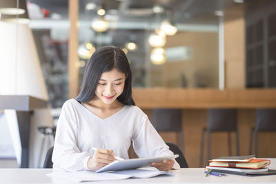 Young woman looking away while sitting on table