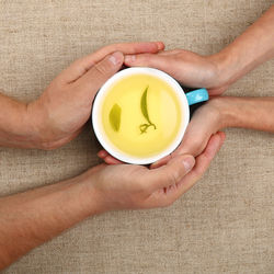 Directly above shot of couple holding green tea at table