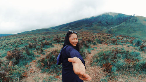 Portrait of woman standing on landscape against mountains