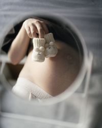 Reflection of pregnant woman with baby booties in mirror