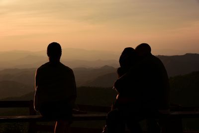 Rear view of silhouette men against mountains during sunset