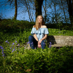 Portrait of teenage girl sitting on bench in park