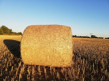 Hay bales on field against clear sky