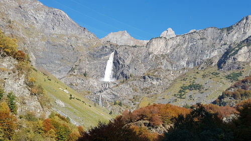 Low angle view of rocky mountains against sky and waterfall in italian alps 