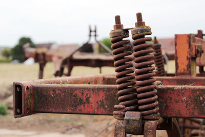 Close-up of rusty machine part against sky