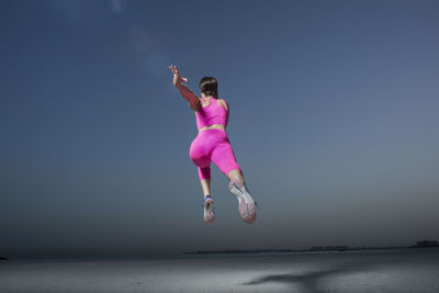 Full length of woman jumping against sky
