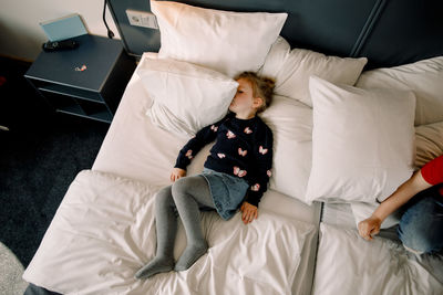 High angle view of girl lying on bed in hotel room