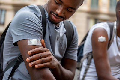 Afro men friends vaccinated showing his arm