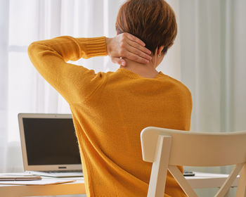 Back view of faceless woman feeling pain in neck. remote work discomfort. working from home