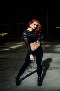 Portrait of beautiful woman with hand on hip standing at abandoned building