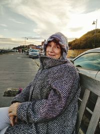 Portrait of woman standing by car against sky