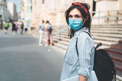 Portrait of young woman standing on street in city