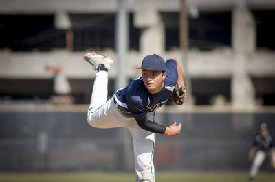 Teen baseball player pitcher in blue uniform on the mound