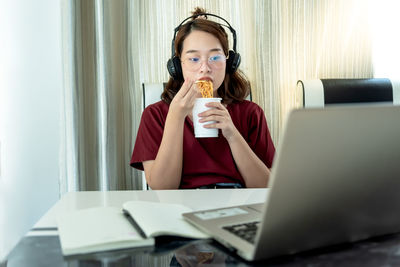 Midsection of woman holding mobile phone while sitting on table