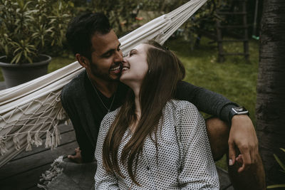 Smiling couple kissing while enjoying in yard during social gathering