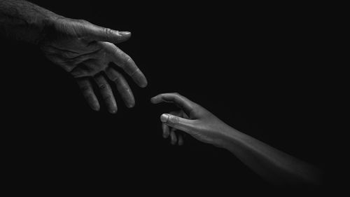 Close-up of hand touching finger against black background
