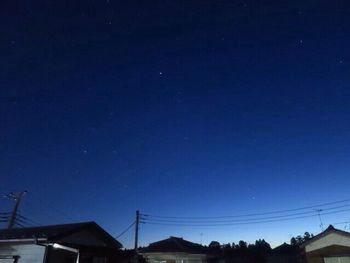 Low angle view of electricity pylon against sky at night