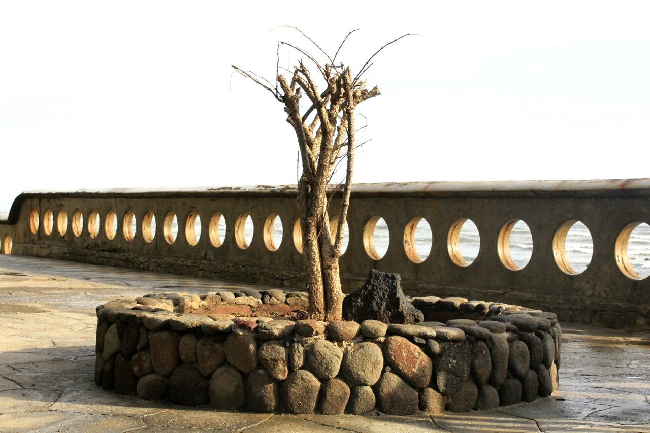 clear sky, copy space, rock - object, stone - object, built structure, nature, architecture, no people, wall - building feature, old, stone wall, outdoors, tranquility, beach, abandoned, day, stone, sunlight, sky, building exterior