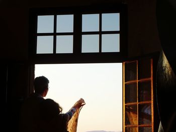 Rear view of man looking through window
