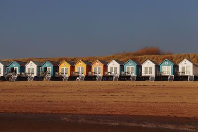 Houses on beach by buildings against sky