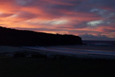 Scenic view of lake against dramatic sky during sunset