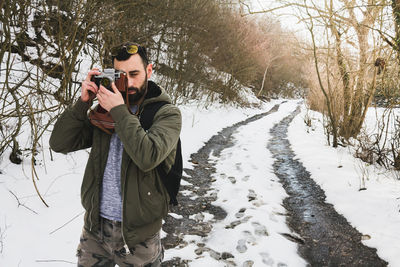 Man photographing with umbrella standing in snow