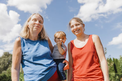 Low angle view of happy family standing against sky