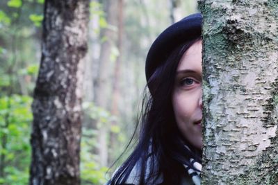 Portrait of teenage girl against tree trunk in forest