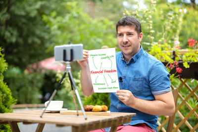 Portrait of man holding ice cream standing by plants