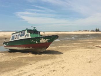 Boat moored on beach against sky