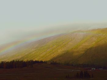 Scenic view of rainbow over land against sky