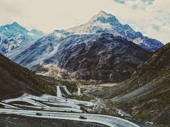 Cars on road against snowcapped mountains and sky