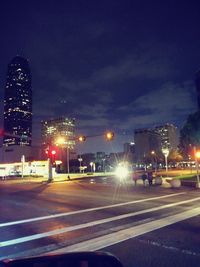 Illuminated city street against sky at night