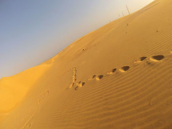 Sand dunes in desert against clear sky