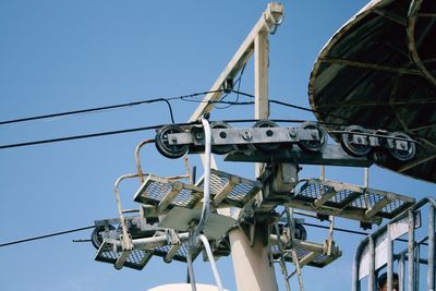 Low angle view of ski lift against blue sky