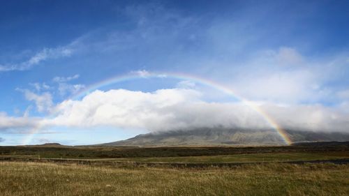 Scenic view of rainbow over landscape against sky