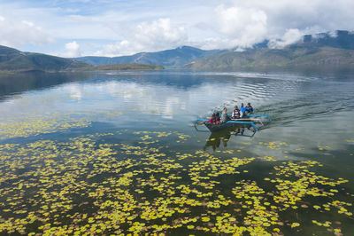 People on lake against sky