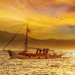 Sailboat in sea against sky during sunset