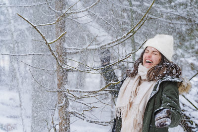 Portrait of smiling woman with snow covered tree