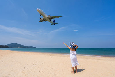 Full length of airplane flying over sea against sky