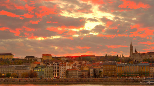 Cityscape against cloudy sky at sunset