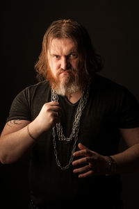 Portrait of man holding camera over black background