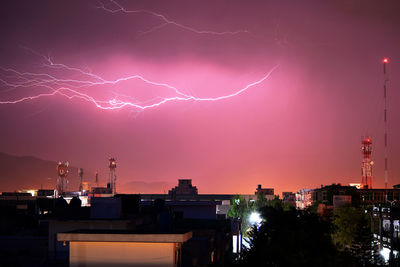 Lightning in city against sky at night