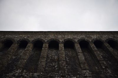 Low angle view of brick wall against clear sky