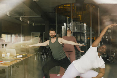 Multiracial colleagues practicing yoga in office