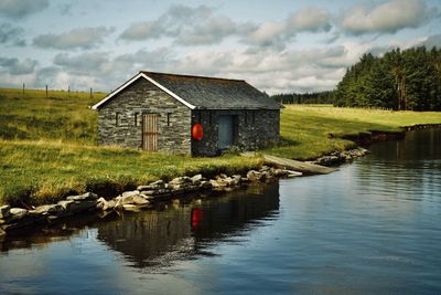 House by lake against sky