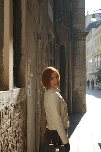 Portrait of woman standing by building in city