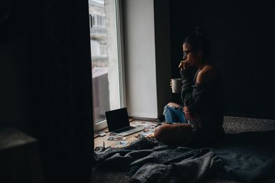 Woman drinking coffee while sitting on floor at home