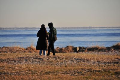 Men standing on beach against clear sky