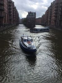 Boats in canal amidst buildings in city